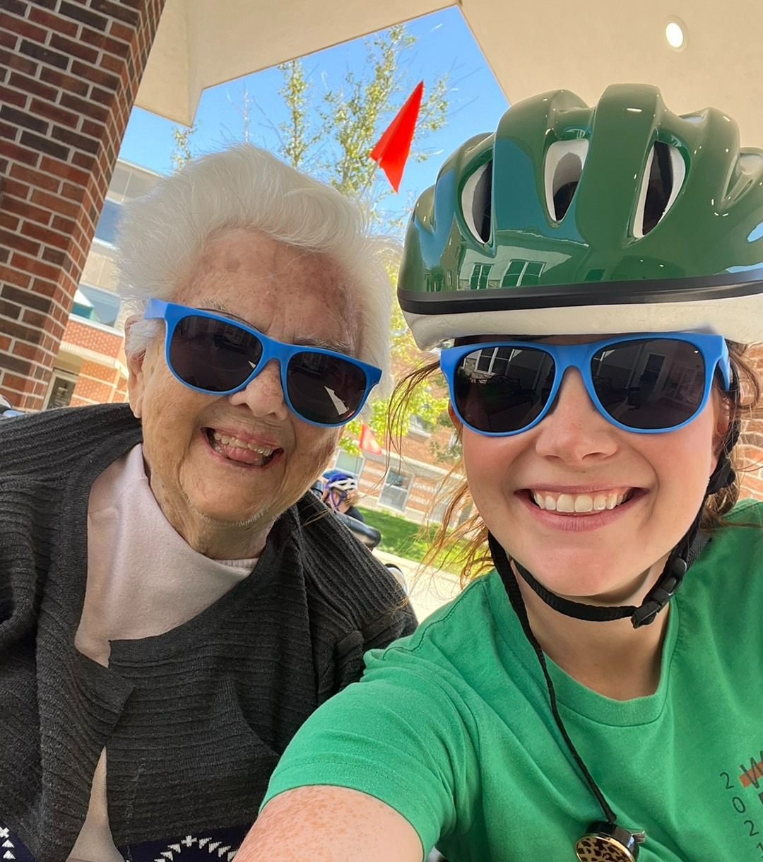 caretaker and senior posing for a photo and smiling while wearing the same sunglasses