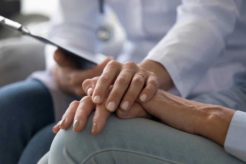 A young doctor holding a senior patient’s hand.