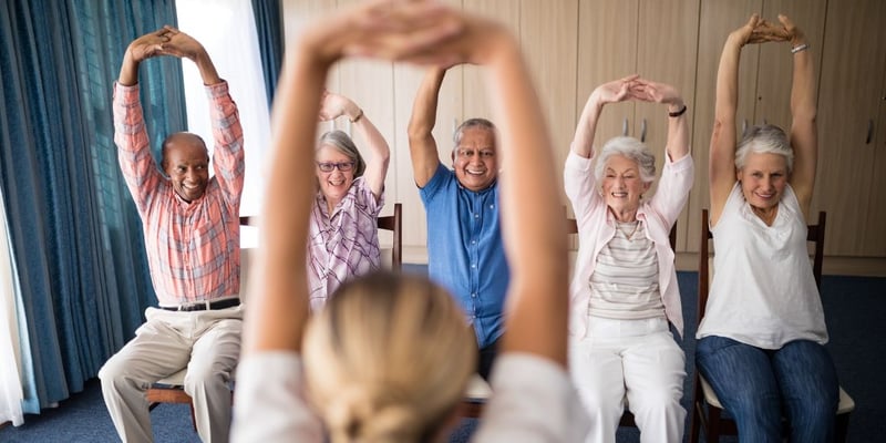 A group of cheerful senior men and women taking an exercise class together.