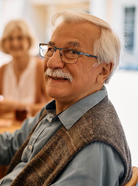 Happy senior man playing poker with his friends at retirement community