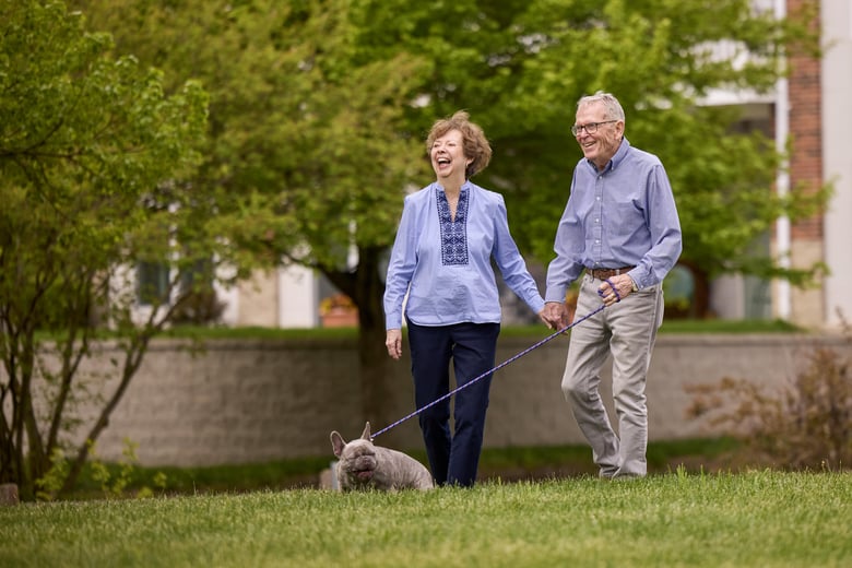 Older couple enjoying their walk with their Frenchie