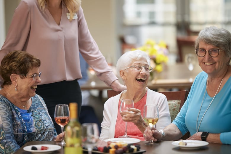 Group of older woman enjoying lunch with drinks and laughing
