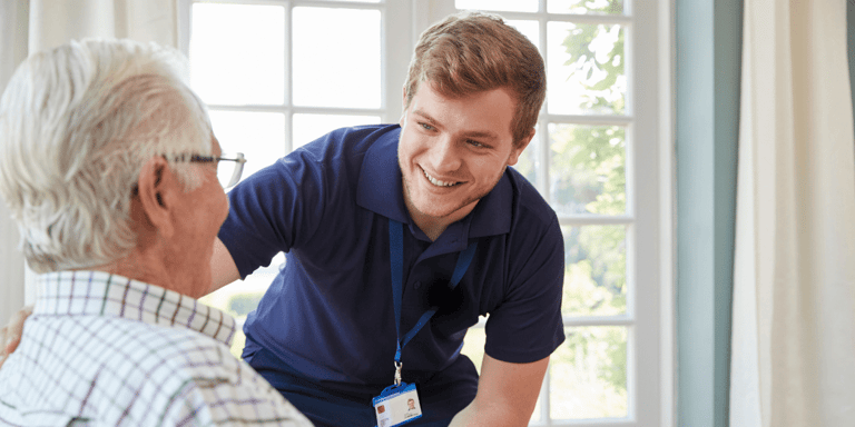 A care worker serving dinner to an older adult man in his home