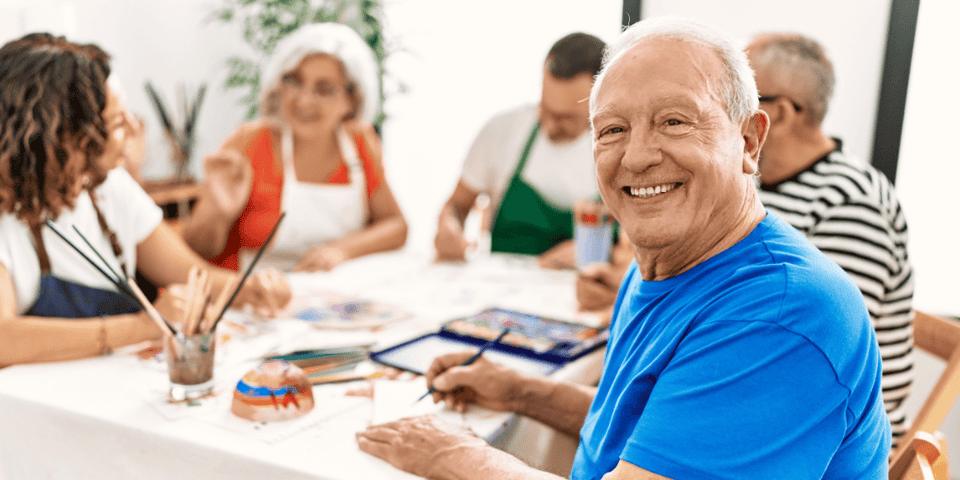 A group of older adults sitting around a table and painting