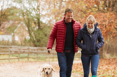 Woman and man walking their dog outside