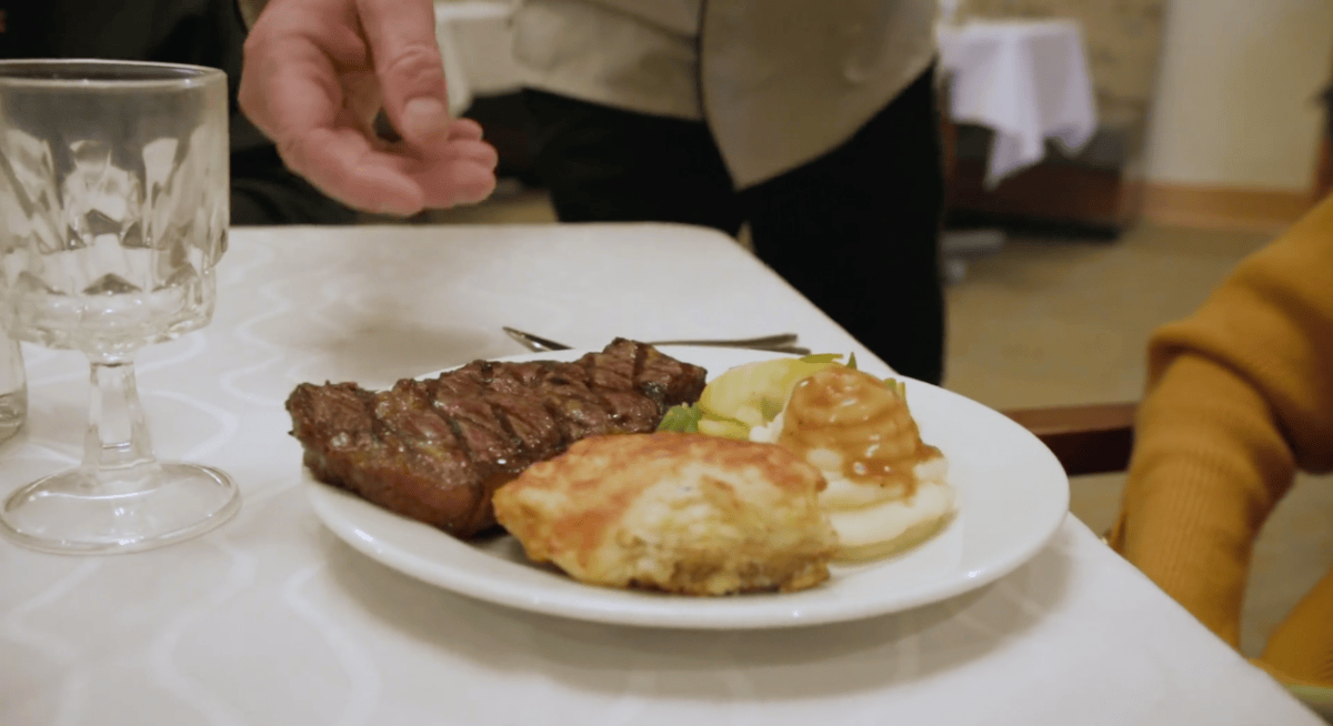 Closeup of a steak, mashed potatoes, and biscuit on a table.