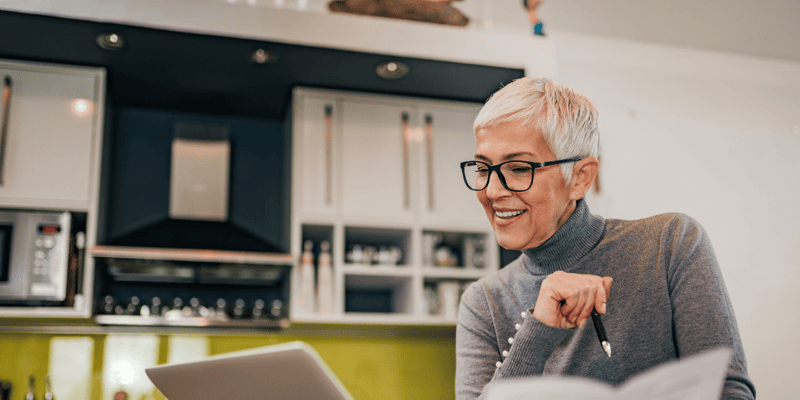 A happy older woman reviewing independent living costs on her laptop
