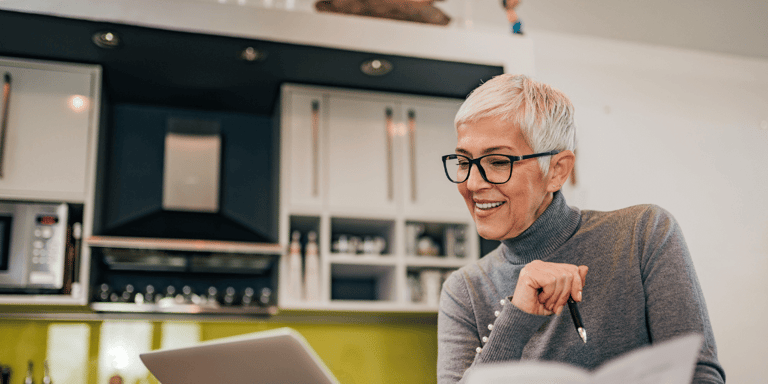 A happy older woman reviewing independent living costs on her laptop